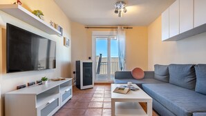 A modern living room with a flat-screen TV, a sofa, a coffee table, and a large window with a view of the outside. - Superior Apartment 31 C with Mountain Views, Private Terrace, and Wi-Fi (Sierra Nevada)