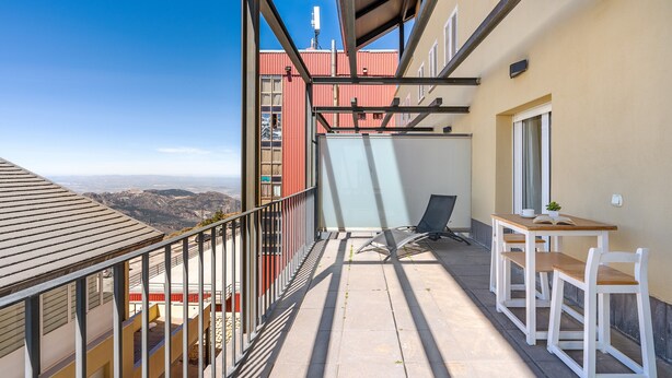 A balcony with a view of the mountains, a table with chairs, and a window. - Superior Apartment 31 C with Mountain Views, Private Terrace, and Wi-Fi (Sierra Nevada)