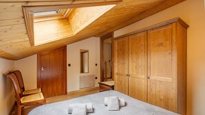 Un dormitorio con tragaluz, armario de madera y una cama con toallas.