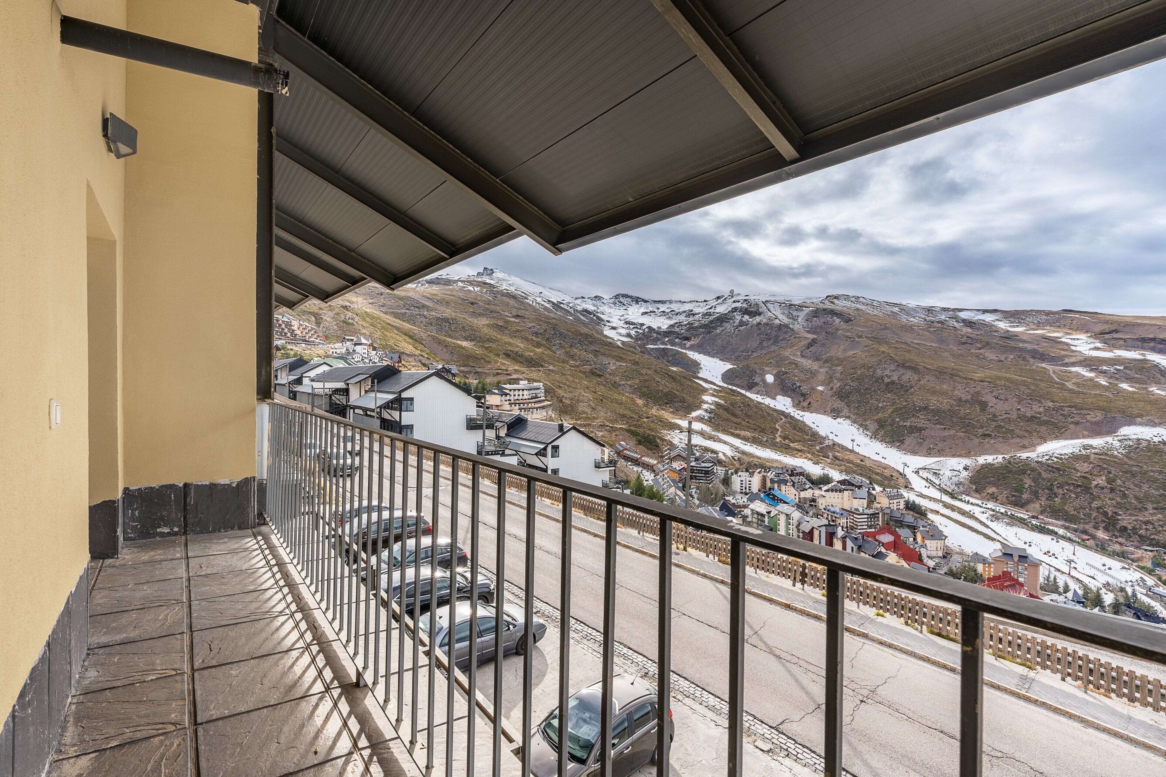 Ein Balkon mit Blick auf eine verschneite Berglandschaft und eine Stadt darunter.