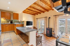 A kitchen with wooden cabinets, a granite countertop, a TV, and a fireplace.