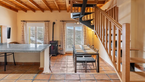 Un comedor con mesa y sillas, una chimenea y una escalera de madera.