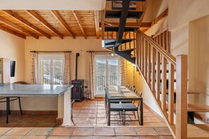 A dining area with a table and chairs, a fireplace, and a wooden staircase.