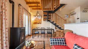 Una sala acogedora con chimenea, una mesa de comedor con sillas, una escalera y un sofá rojo.