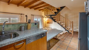 Una cocina con encimeras de granito, armarios de madera, un lavamanos de acero inoxidable, lavavajillas empotrado y un refrigerador negro.