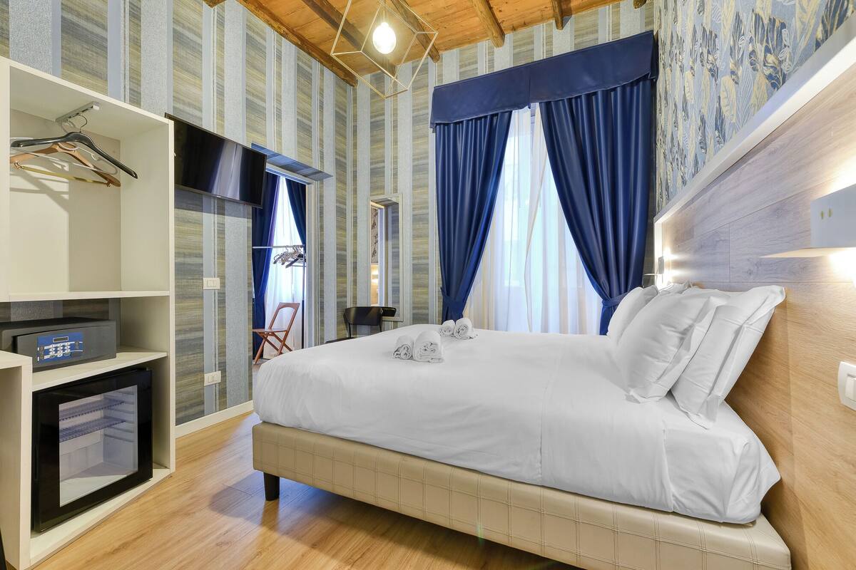 A bedroom with a bed, a TV, a wardrobe, and a desk with a computer.