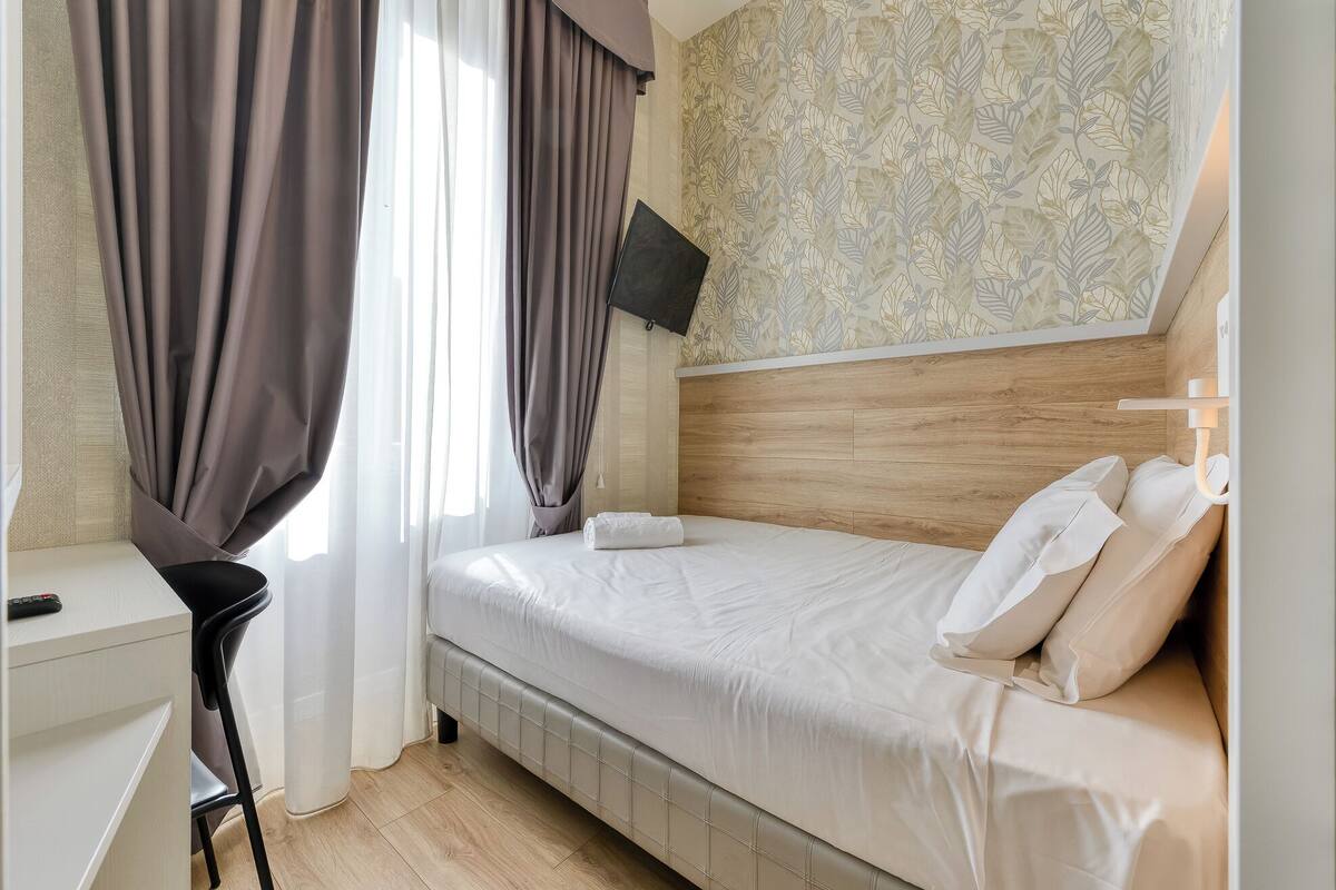 A bedroom with a bed, a desk, and a chair.