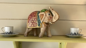 Une étagère ornée d’une statuette d’éléphant décorative, de deux tasses et de trois mugs.