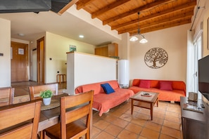 A living room with a wooden ceiling, a sofa, a dining table, and a TV. - Holiday Apartment "Duplex 23 E" with Mountain Views, Private Terrace and Wi-Fi (Monachil)