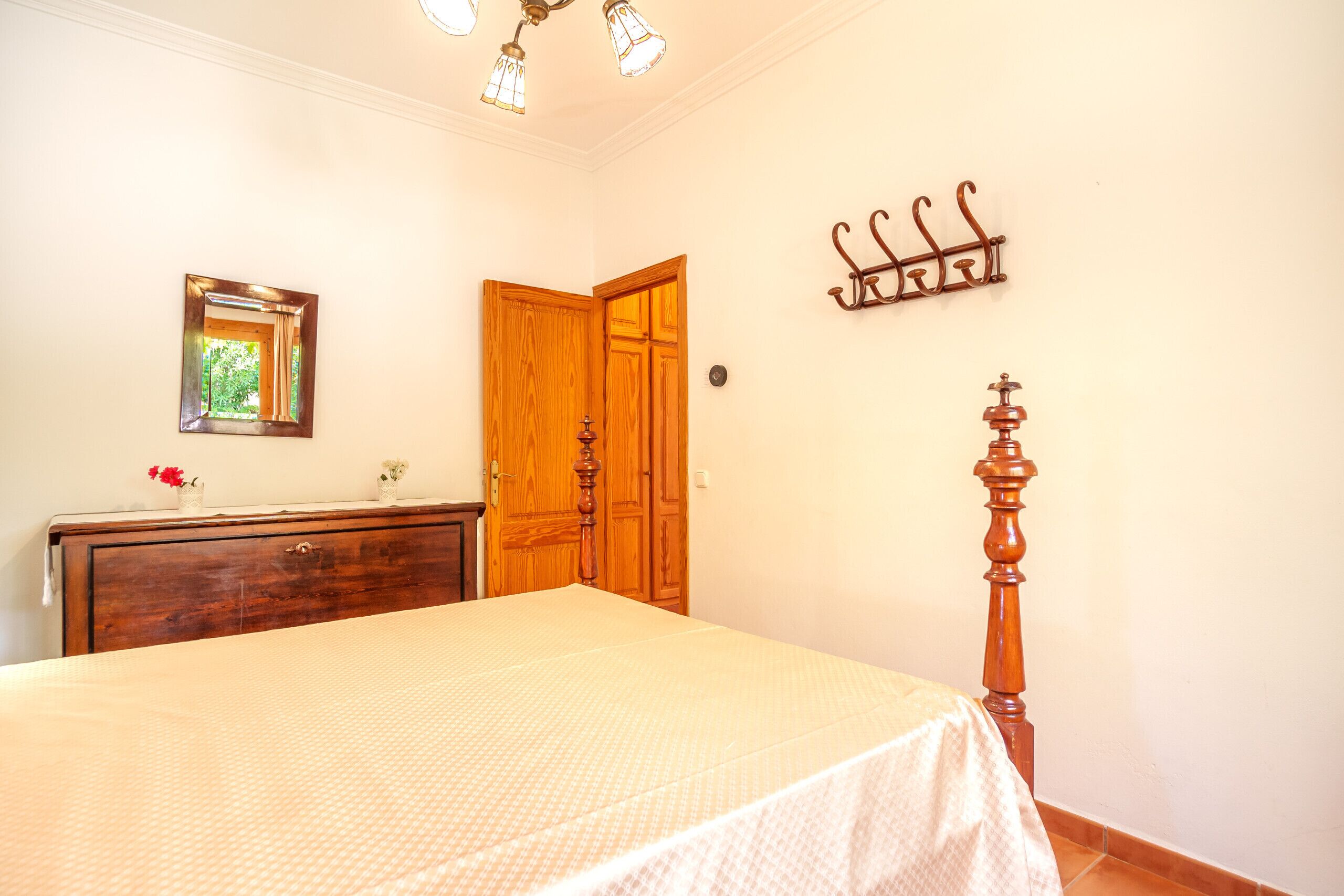 Un dormitorio con cama, cómoda de madera y puerta de madera.