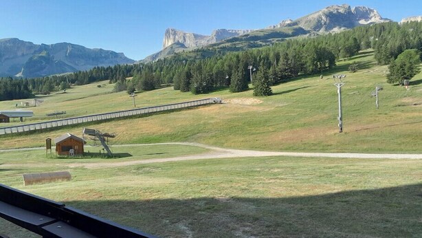 A rural landscape with a wooden cabin, a dirt path, and a mountain range in the background. - Ski in and ski out apartment Superdévoluy (Le Dévoluy)
