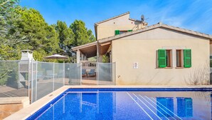 A swimming pool with a glass enclosure, a covered patio, and a building with green shutters. - Rental Villa Manresa in Alcudia by JS Villas (Alcudia)