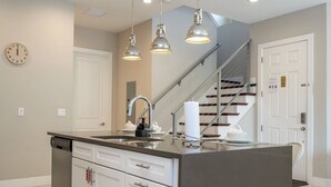 Una cocina moderna con una isla central, electrodomésticos de acero inoxidable e iluminación colgante.
