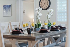 A dining table set with plates, bowls, and glasses, surrounded by chairs.