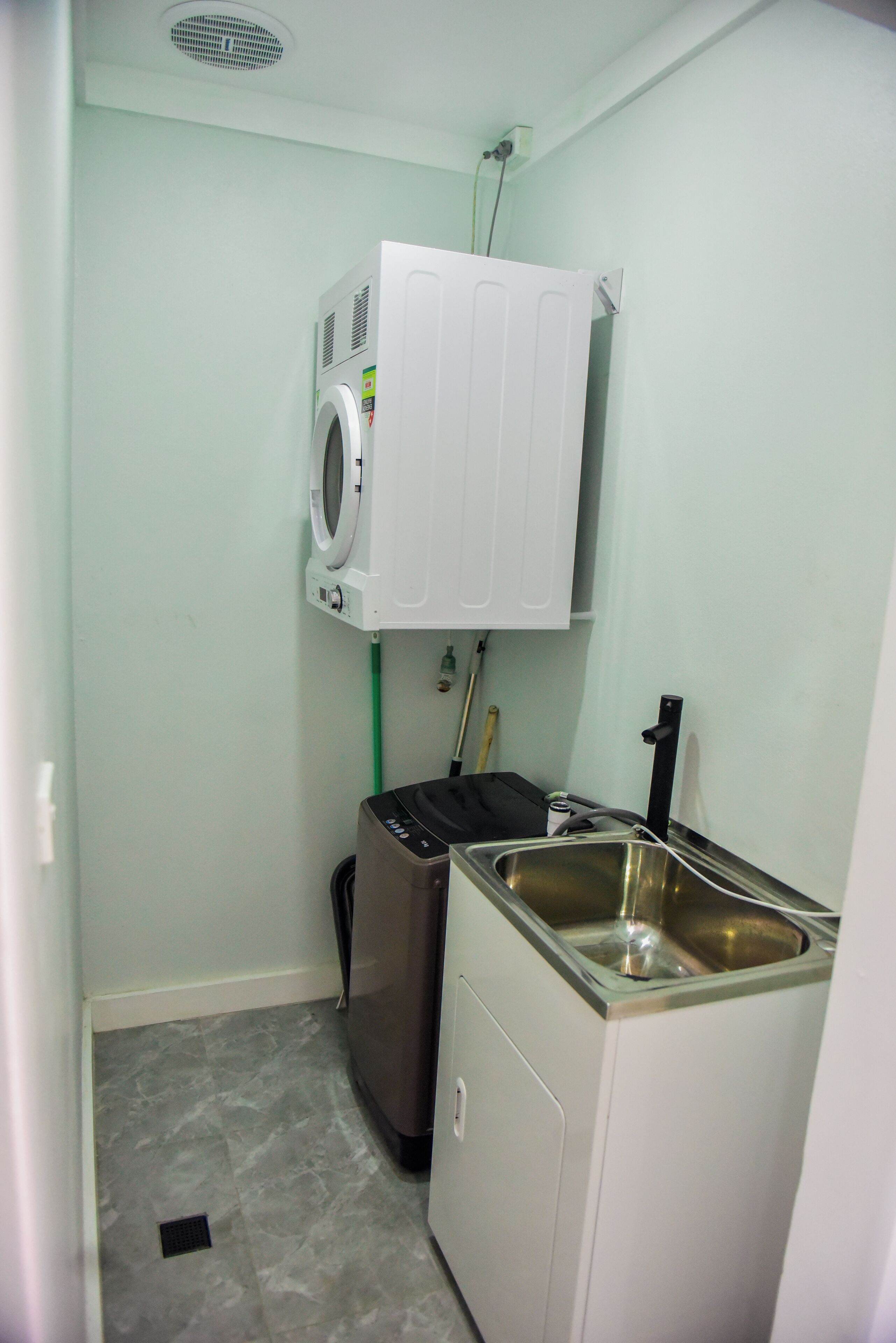 A laundry room with a washing machine, a dryer, and a sink.
