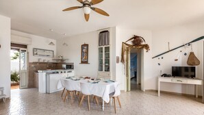 Un'ampia cucina con zona pranzo, una ventola a soffitto e una TV su una scrivania.