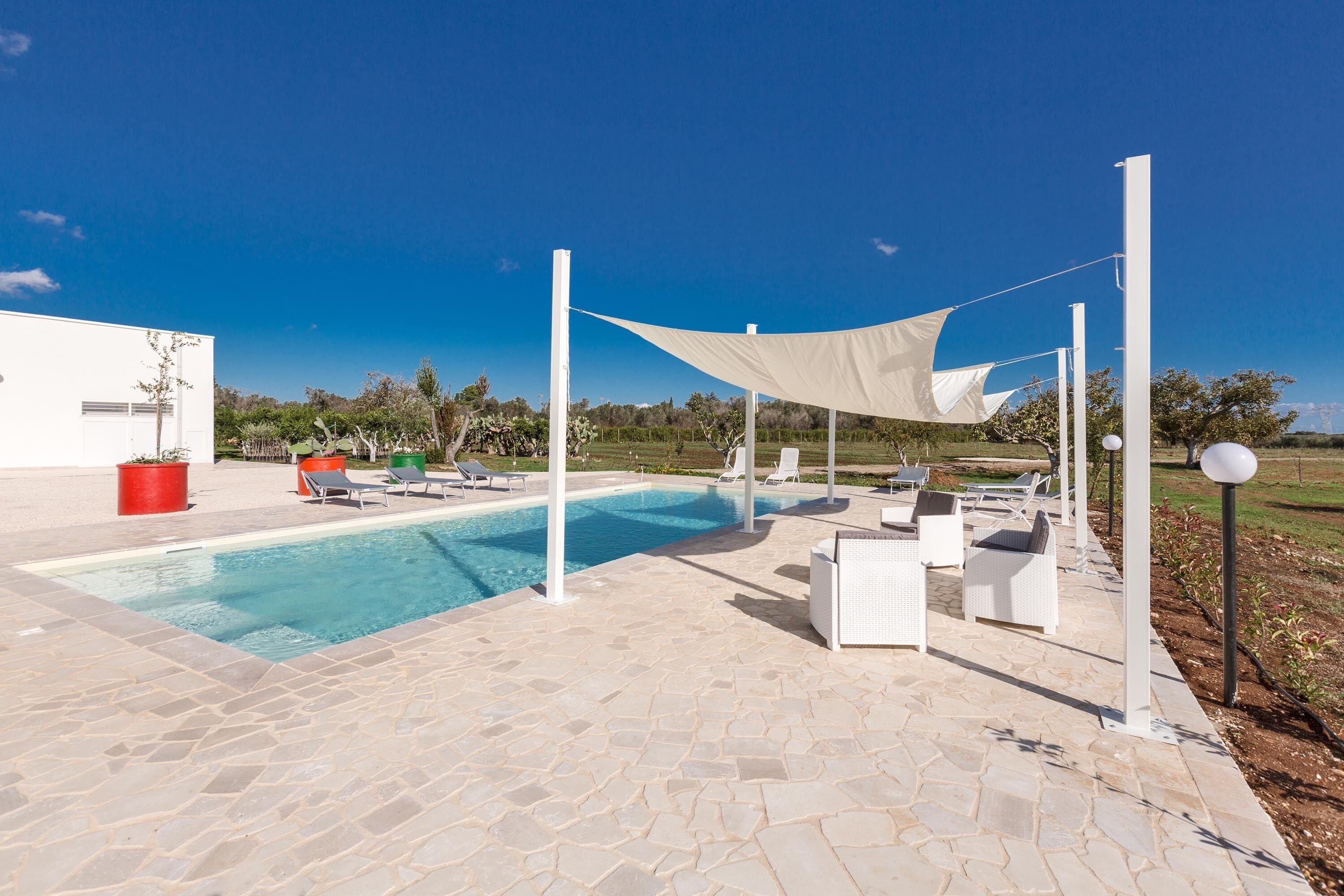 Un espace piscine avec des chaises longues et un auvent ombragé.