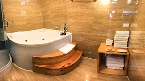A modern bathroom with a large bathtub, wooden vanity, and a towel rack. - Suites Machupicchu (Machu Picchu)