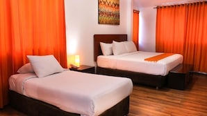 A hotel room with two beds, wooden flooring, and orange curtains. - Suites Machupicchu (Machu Picchu)