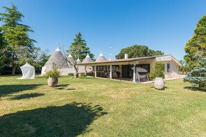 Ein traditionelles Steinhaus mit Ziegeldach, umgeben von einem gepflegten Rasen und Bäumen.