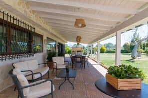 Ein überdachter Patio-Bereich mit Gartenmöbeln, darunter ein Tisch und Stühle, sowie ein Blumentopf.