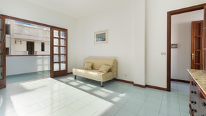 A room with a beige sofa, a wooden cabinet, and a door leading to another room.