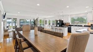 Una cocina amplia con una isla central, electrodomésticos modernos y mucha luz natural proveniente de ventanas grandes.