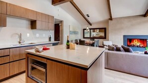 Une cuisine moderne avec des meubles en bois, un four encastré et un coin repas agrémenté d’une cheminée.