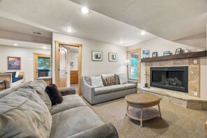 Un salon moderne avec une cheminée, un ensemble de canapés, une table basse et un coin repas comprenant une table et des chaises en bois.