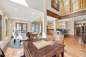 Un vaste espace de vie comprenant une table à manger, un jeu d’échecs et donnant sur la cuisine.