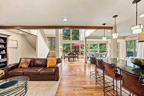 A spacious living area with a leather sofa, a glass coffee table, and a dining area with a bar. - Golf Course House w/ Hot Tub, Near Vail & BC (Avon)