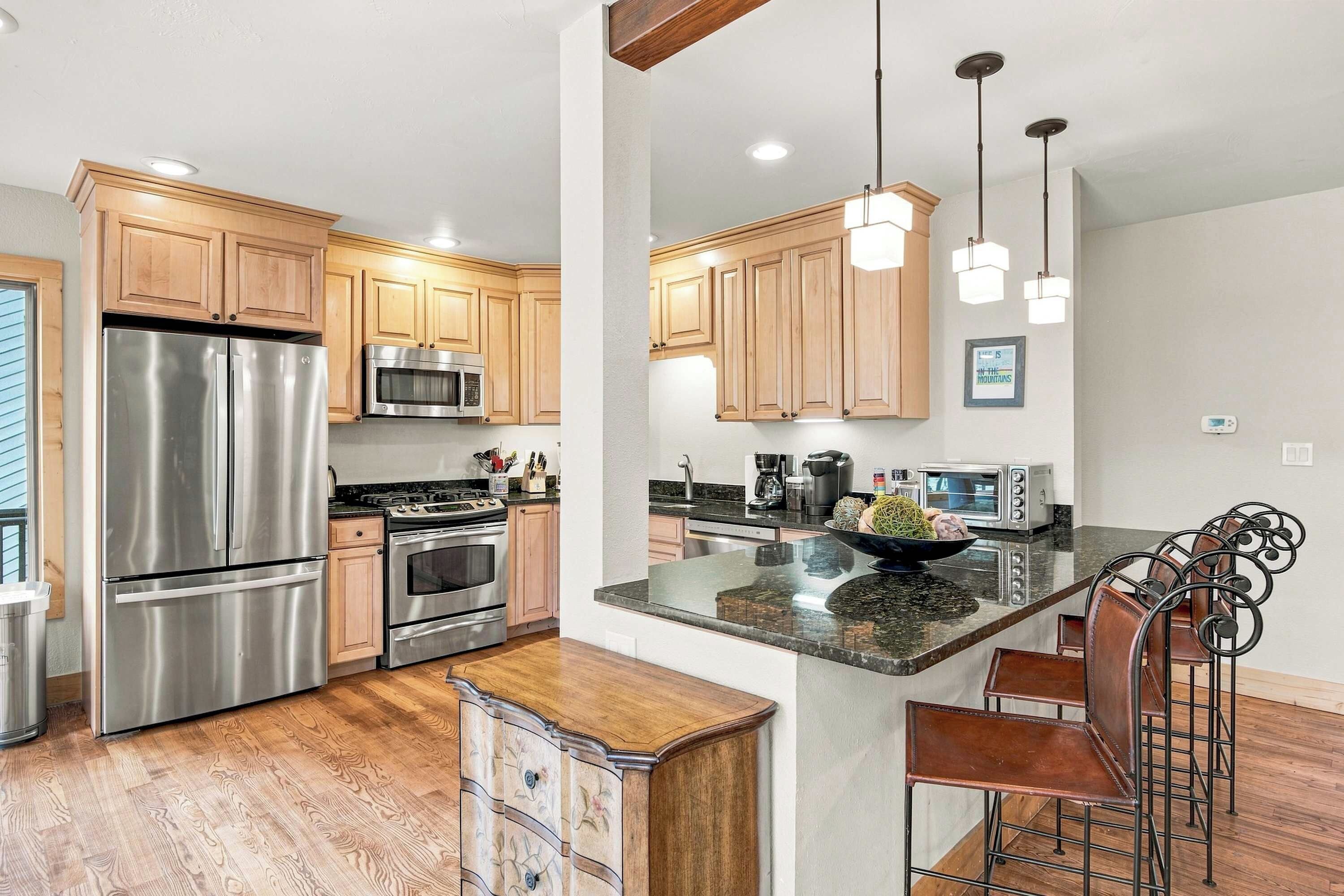 A modern kitchen with stainless steel appliances, wooden cabinets, and a central island with bar stools.