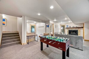 A spacious living area with a foosball table, a fireplace, and a staircase leading to another level. - Golf Course House w/ Hot Tub, Near Vail & BC (Avon)