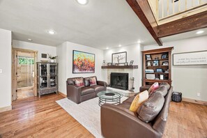 A living room with a fireplace, a sofa, a coffee table, and a bookshelf.