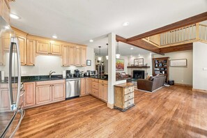 A spacious kitchen with wooden cabinets, a dishwasher, and a dining area with a sofa and a fireplace.