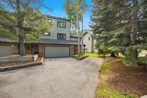 A two-story house with a garage, a front porch with a bench, and a driveway leading to the garage.