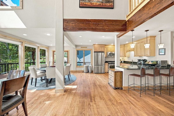 A modern kitchen with wooden cabinets, stainless steel appliances, and a bar area.