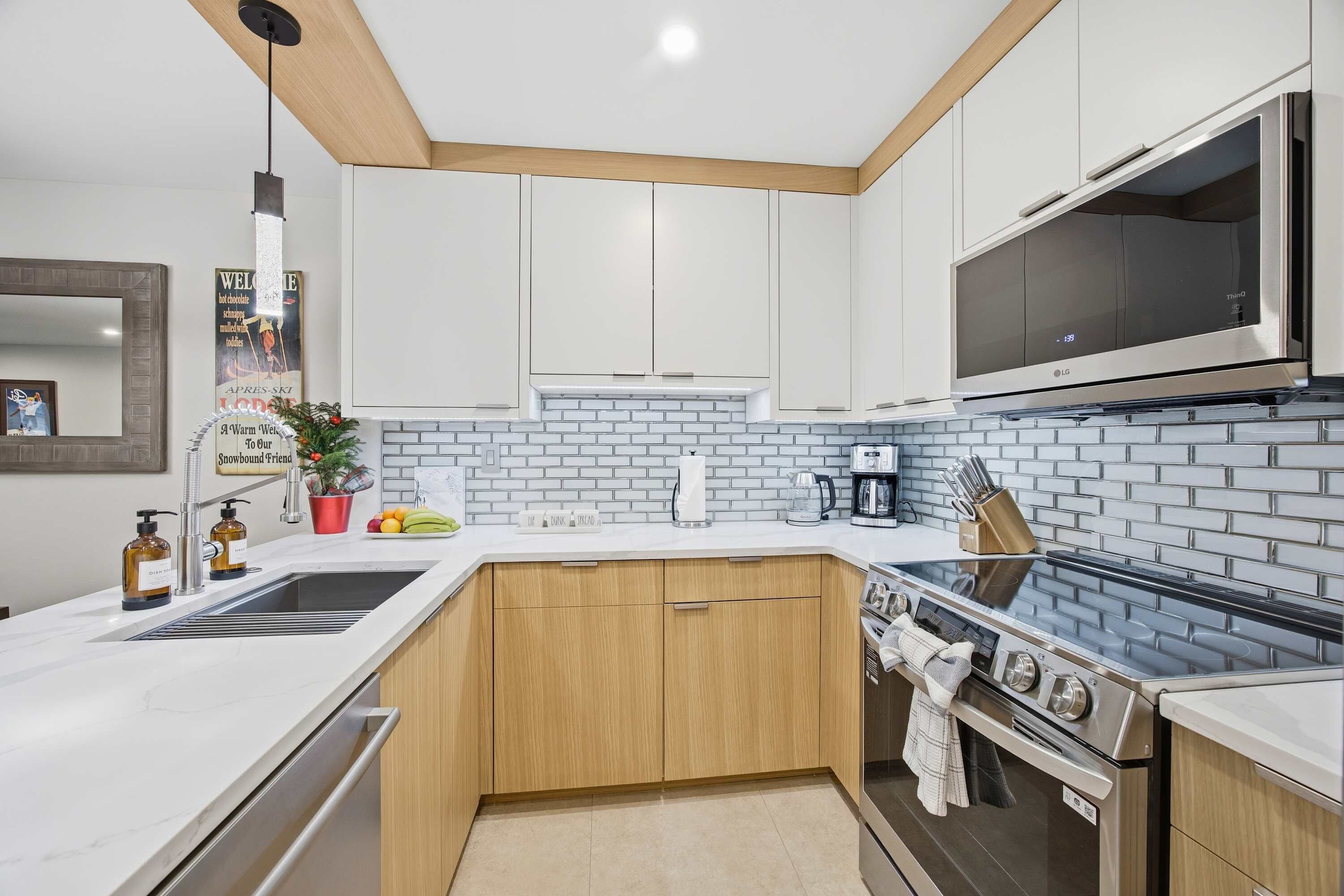 Une cuisine moderne avec des meubles blancs, un four à micro-ondes en acier inoxydable et une cuisinière noire.