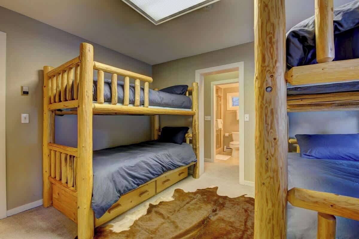 A bunk bed room with a skylight, a wooden headboard, and a leather-like rug.