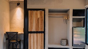 Una habitación con puerta de madera, una silla, un estante con una escultura y una ventana con vistas.