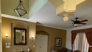 A spacious living room with a high ceiling, a ceiling fan, a large mirror, and a round patterned rug. - Spacious 4BD/4BA Dream Villa w/LRG Backyard in PSL (Port St. Lucie)