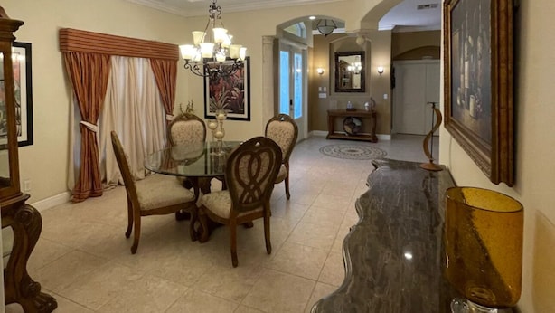 A dining area with a glass table, wooden chairs, a chandelier, and a marble countertop. - Spacious 4BD/4BA Dream Villa w/LRG Backyard in PSL (Port St. Lucie)