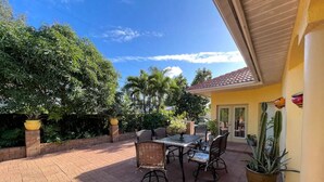 An outdoor patio with a table and chairs, surrounded by potted plants and a brick wall. - Spacious 4BD/4BA Dream Villa w/LRG Backyard in PSL (Port St. Lucie)