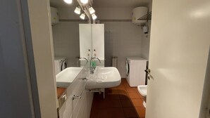 Un baño con dos lavamanos, un espejo, un inodoro y una lavadora.