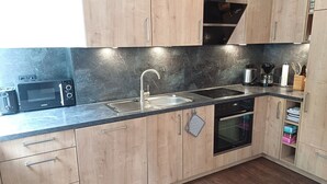 Une cuisine moderne avec des meubles en bois, un évier en acier inoxydable, un four à micro-ondes, un grille-pain et un four traditionnel.