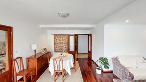 Un coin repas avec une table dressée pour quatre personnes, des chaises en bois, un buffet en bois et une tapisserie à motifs.
