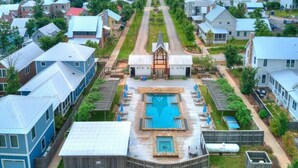 A residential area with a central swimming pool, surrounded by houses with metal roofs, and a church with a steeple. - Blue Fish on Firefly Park (Carlton Landing)