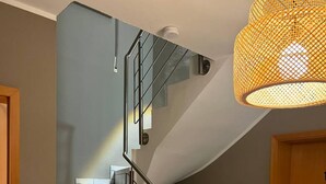 Un escalier avec une rampe en métal, une porte en bois et un luminaire suspendu.