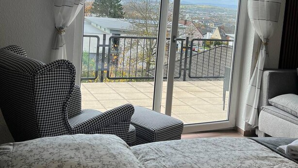 Une chambre avec un balcon, un canapé et un fauteuil.