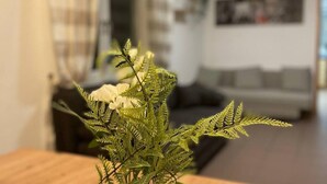 Un salon avec une table en bois, un vase en verre contenant une fougère et un canapé.